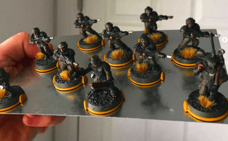 A squad of Guardsmen on orange Squad Marks held upside down on a steel sheet